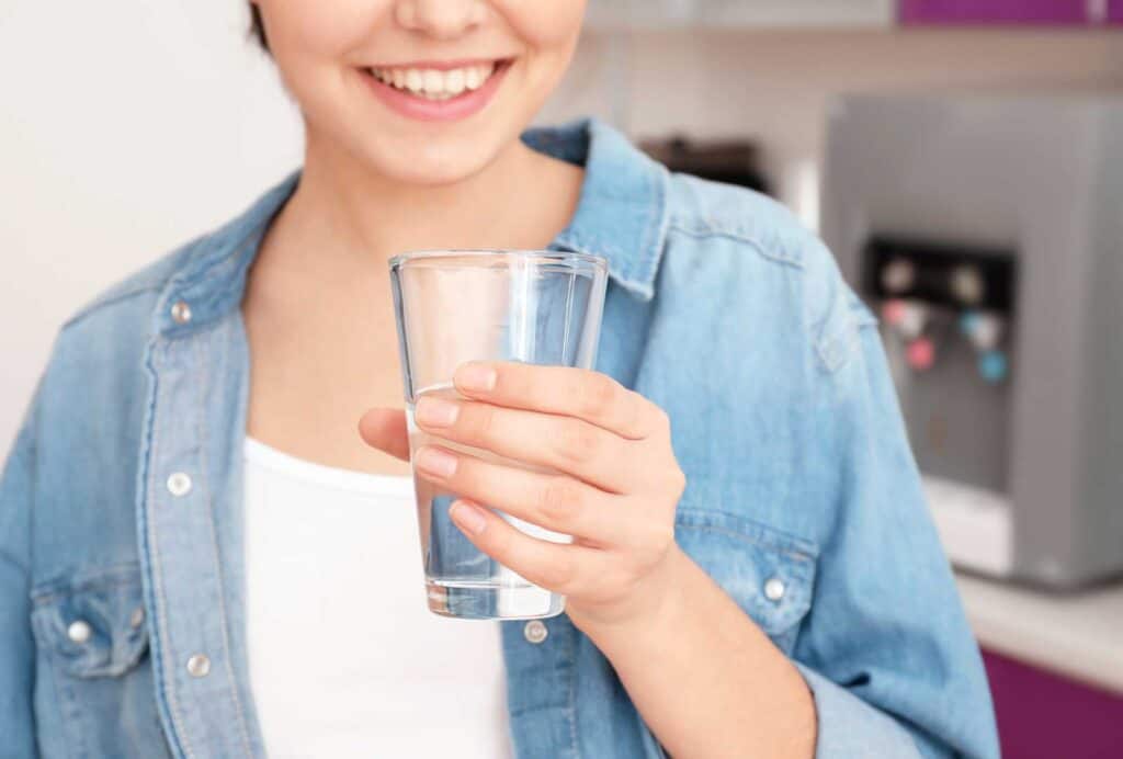 Girl holds in hand a glass of clean drinking water