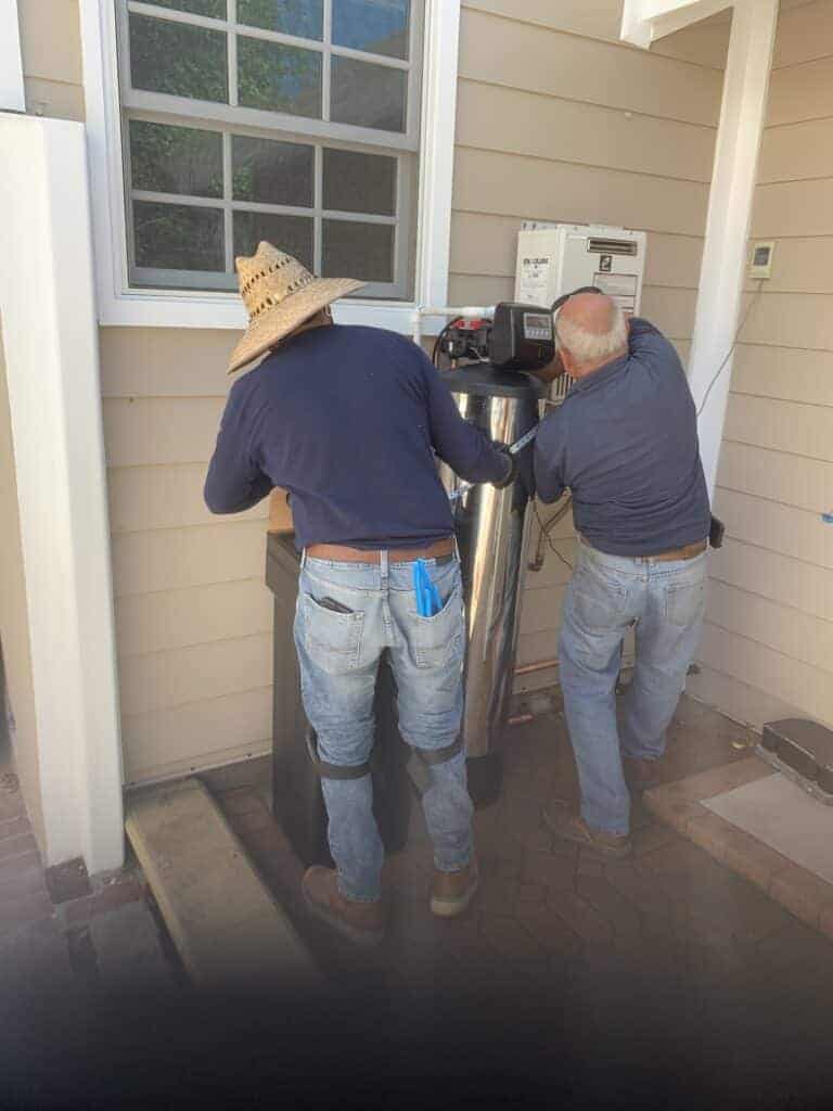 Praz employees fixing meter after installation of a softener system at a home near the los angeles area