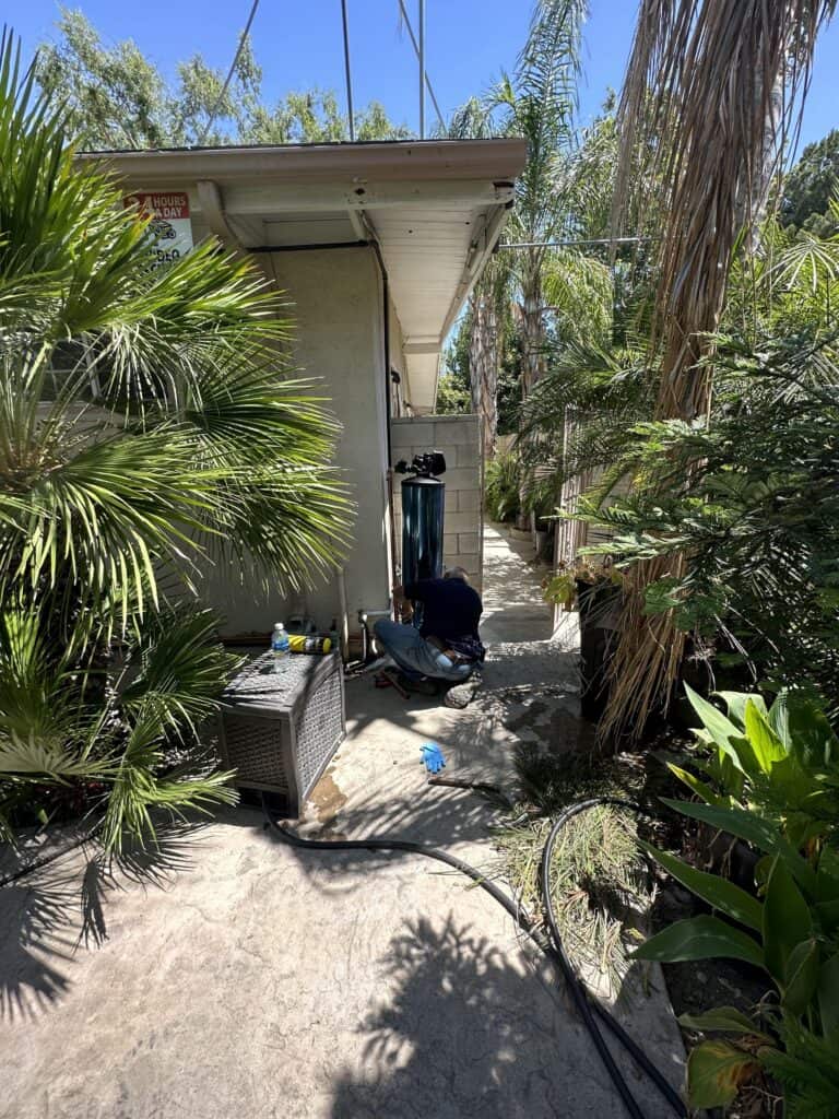 Outdoor installation of the Praz residential softener unit with the new blue tank design in the side of a house in Tarzana California