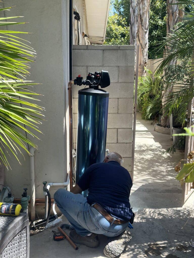close up view of the Praz Signature Softener installation with technician adjusting the blue tank while connecting it to the main pipe line at a home in west hollywood