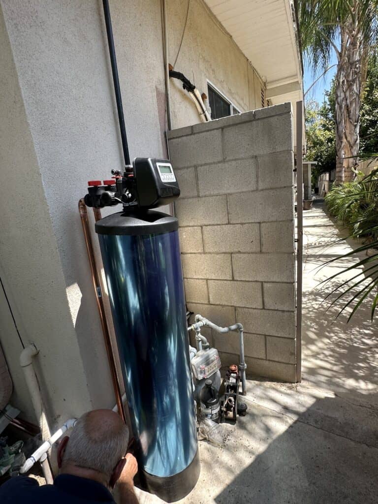 soft water system with blue tank installed in the side of a house in tarzana