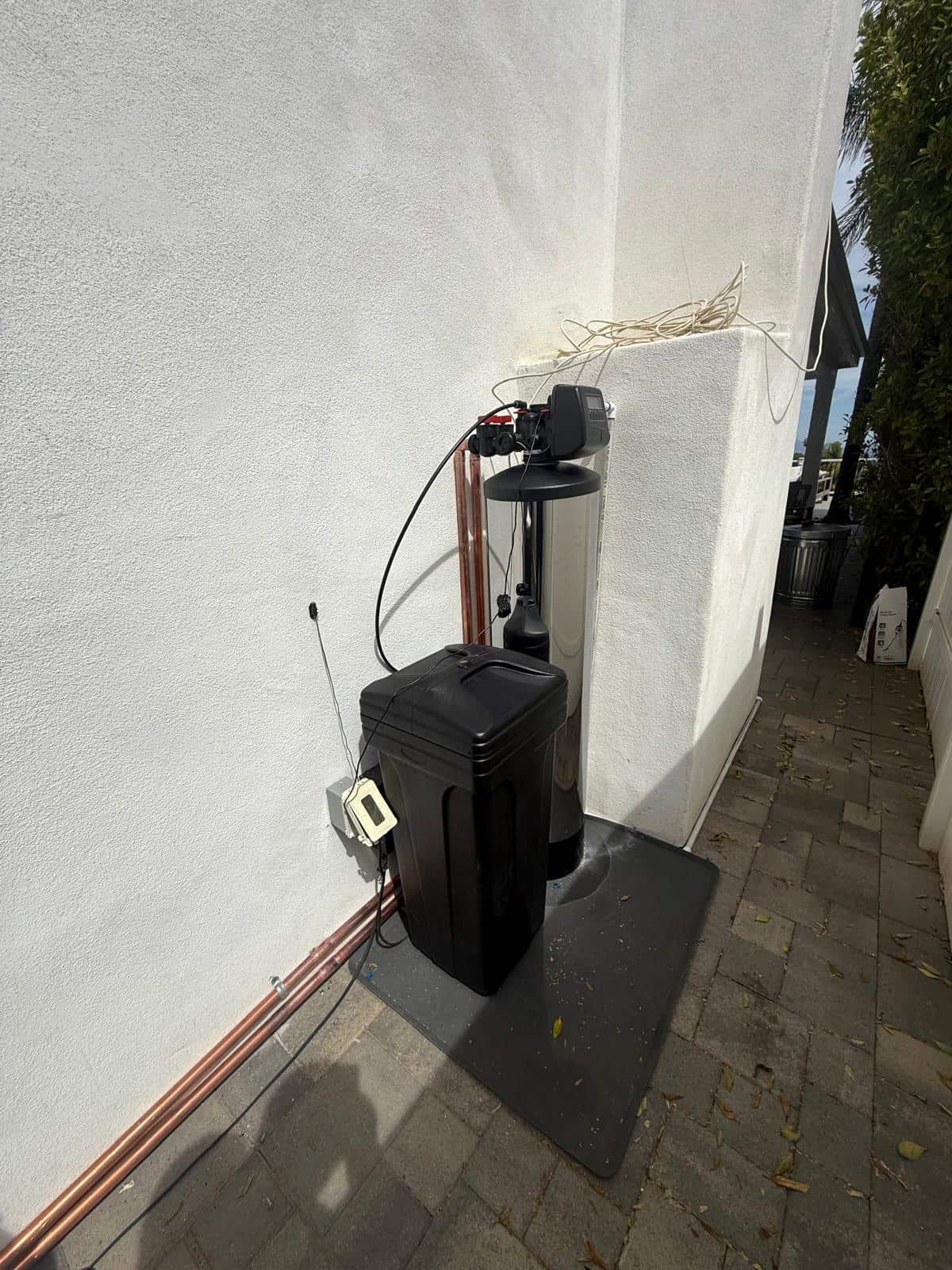 Water softener system installed on a home patio with clean copper line routing
