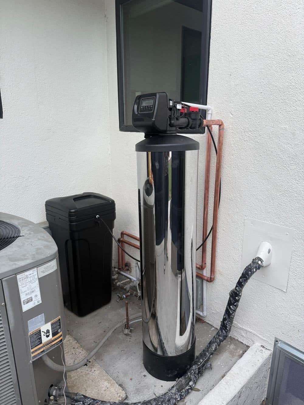 Chrome whole-house water softener with brine tank and copper plumbing installed by Praz Pure Water